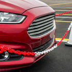 Red car with a chain attached to its front, on a road.