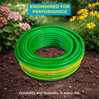 green and yellow garden hose on soil with flowers 