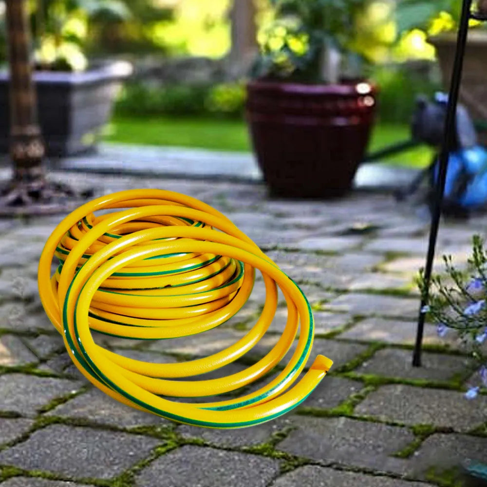 Coiled yellow and green garden hose on a stone patio with plants in the background