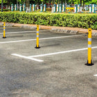 Yellow parking barriers on a paved road with greenery in the background