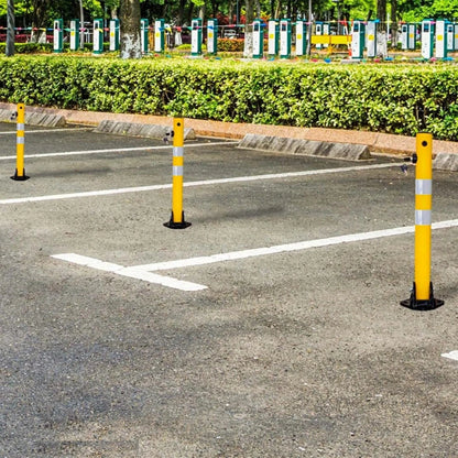 Yellow parking barriers on a paved road with greenery in the background