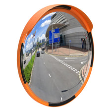 Convex traffic mirror with orange frame reflecting a road scene.